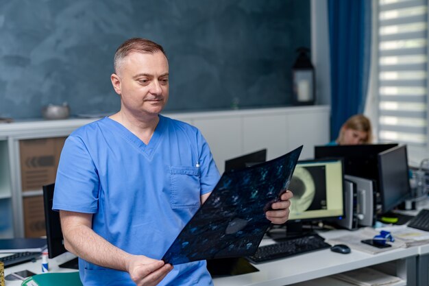 Medico in possesso di un'immagine di un flusso di lavoro di risonanza magnetica cerebrale in ospedale diagnostico. Sanità, roentgen, persone e concetto di medicina.