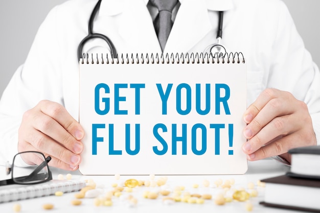 Medico in possesso di una scheda con Get Your Flu Shot, concetto medico
