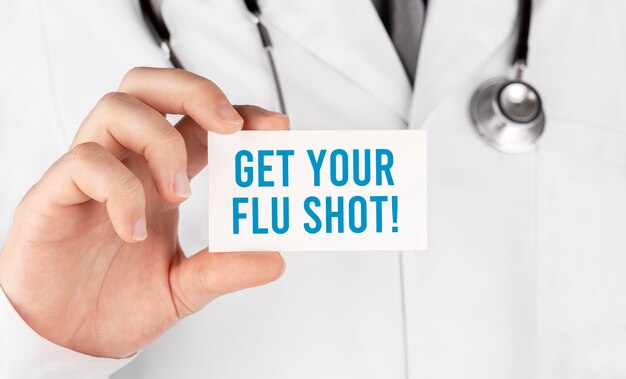 Medico in possesso di una scheda con Get Your Flu Shot, concetto medico