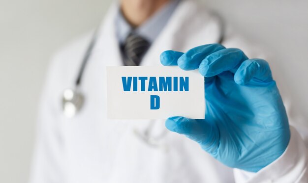 Medico in possesso di una scheda con testo VITAMINA D, concetto medico