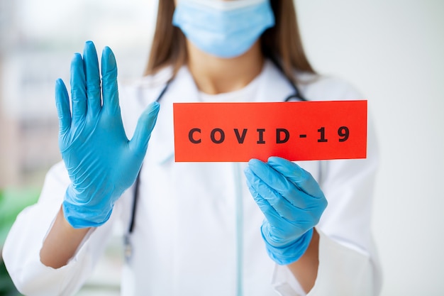 Medico in possesso di una scheda di carta con il testo covid-19.