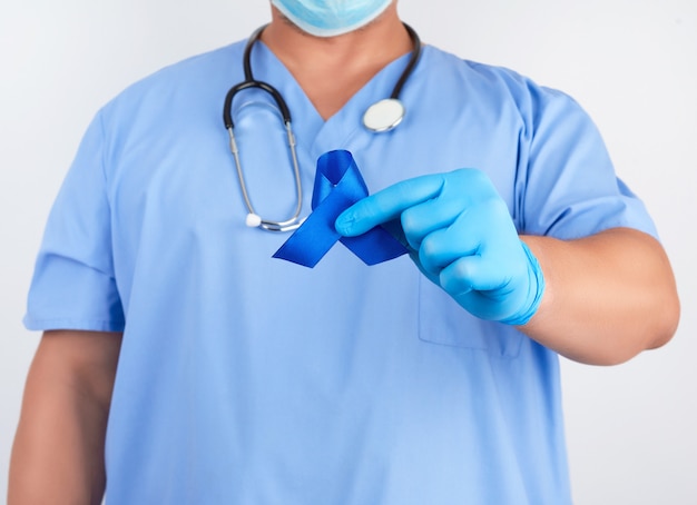 Medico in uniforme blu e guanti di lattice sterili tiene un nastro blu scuro