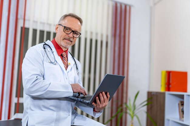 Medico in uniforme medica che lavora con il tablet Medico maschio felice con lo stetoscopio