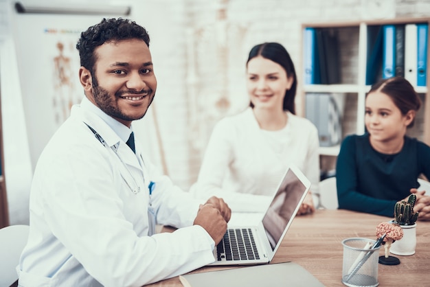 Medico indiano in abito bianco vedendo i pazienti in ufficio