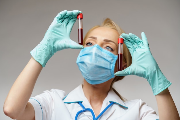 medico infermiera donna che indossa guanti e maschera protettiva