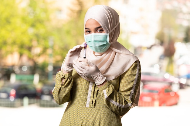 Medico infermiera donna musulmana che indossa maschera e guanti protettivi - tenendo il test del sangue del virus