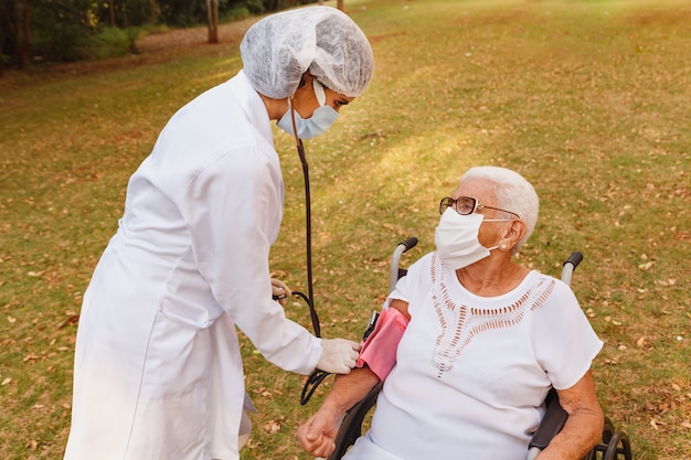 Medico infermiere che misura la pressione della donna anziana