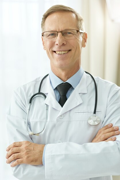 Medico maschio allegro in camice da laboratorio in piedi in clinica