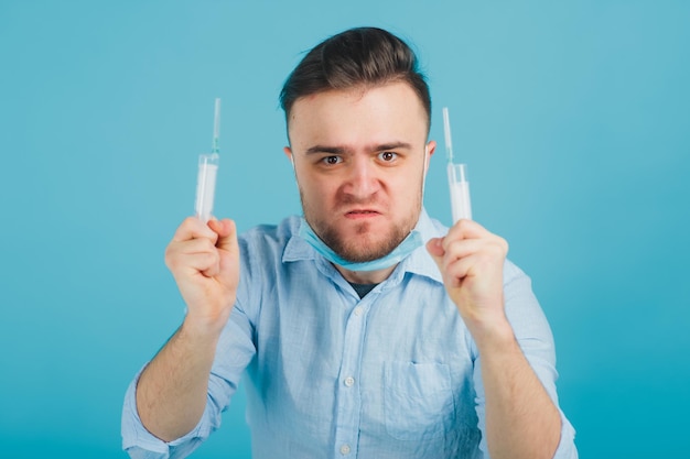 medico maschio barbuto e tenendo la siringa e gridando su sfondo blu