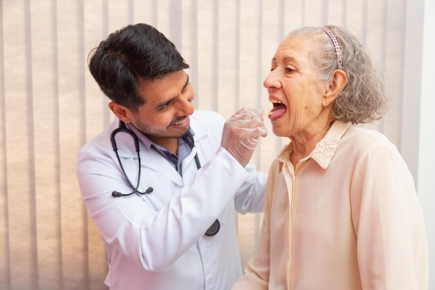 Medico maschio che esamina la gola della donna anziana in consultazione. Medico che controlla la gola della donna anziana