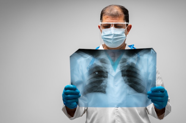 Medico maschio che esamina la scansione a raggi x dei polmoni contro il grigio si chiuda