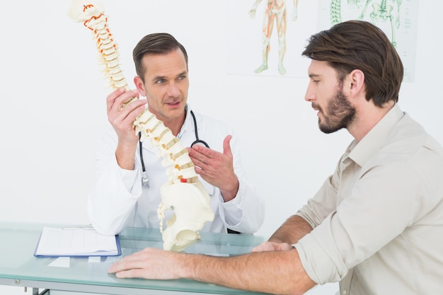 Medico maschio che spiega la spina dorsale ad un paziente