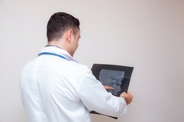medico maschio in camice bianco che esamina raggi x isolato su priorità bassa bianca