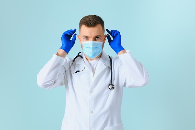 Medico maschio in maschera medica su sfondo colorato