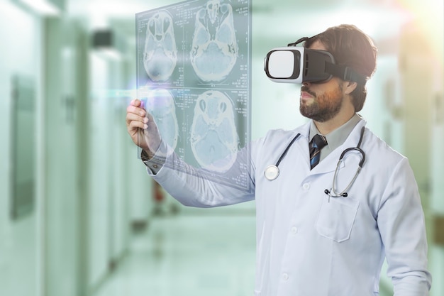 Medico maschio in un ospedale, utilizzando occhiali per realtà virtuale, guardando uno schermo virtuale