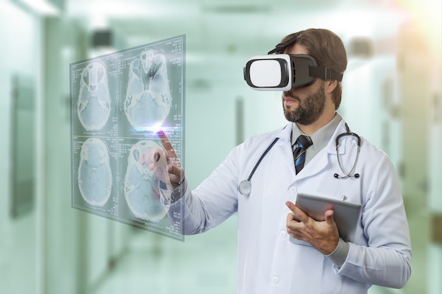 Medico maschio in un ospedale, utilizzando occhiali per realtà virtuale, guardando uno schermo virtuale