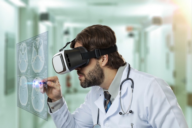 Medico maschio in un ospedale, utilizzando occhiali per realtà virtuale, guardando uno schermo virtuale