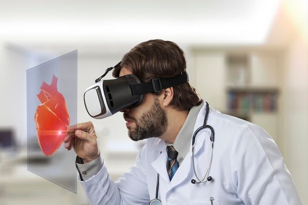 Medico maschio nel suo ufficio, utilizzando occhiali per realtà virtuale, guardando un cuore virtuale