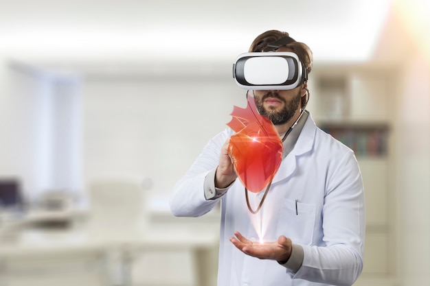 Medico maschio nel suo ufficio, utilizzando occhiali per realtà virtuale, guardando un cuore virtuale