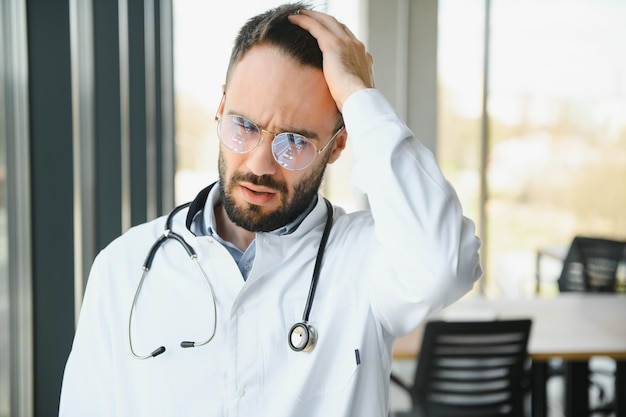 Medico maschio stressato Medico maschio adulto di mezza età che lavora per lunghe ore Medico oberato di lavoro nel suo ufficio Nemmeno i medici sono esenti dal burnout