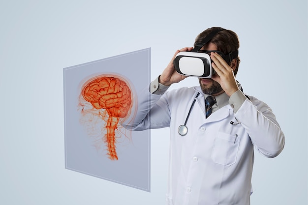 Medico maschio su un muro grigio, utilizzando occhiali per realtà virtuale, guardando un cervello virtuale