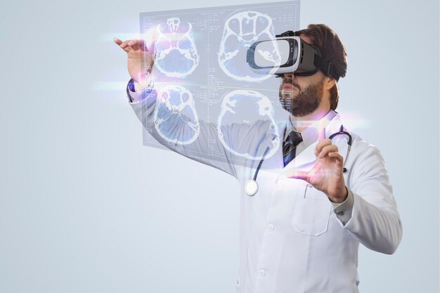 Medico maschio su un muro grigio, utilizzando occhiali per realtà virtuale, guardando uno schermo virtuale