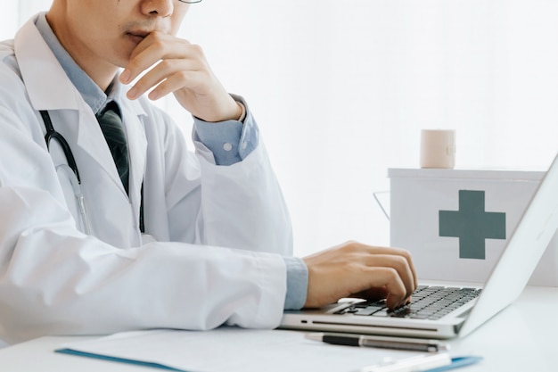 Medico maschio usa computer, ricerca e analisi, analisi delle malattie e registra informazioni sui pazienti,