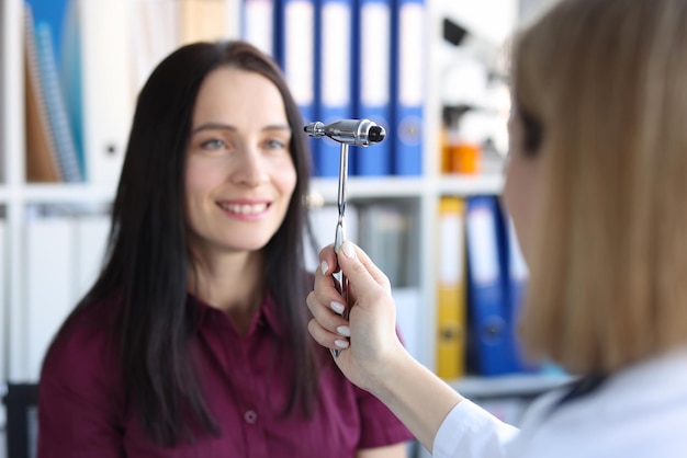 Medico neurologo che guida lo strumento martello davanti agli occhi del paziente in clinica