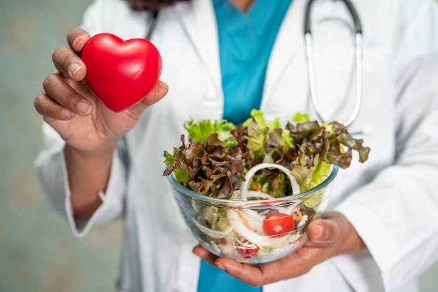 Medico nutrizionista che tiene varie verdure fresche sane per il paziente.