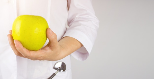 Medico nutrizionista mano sull'anca che mostra mela verde. La mano del medico nutrizionista che tiene una mela verde fresca. Dieta sana.