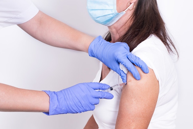 Medico o infermiere femminile che dà colpo o vaccino ai pazienti vaccinazione del primo piano della spalla
