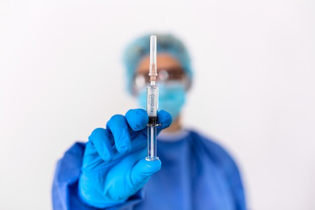 Medico o scienziato in uniforme da suite PPE che tiene il vaccino liquido della medicina