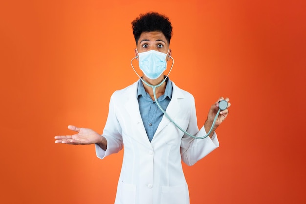 Medico o veterinario isolato nero giovane residente medico con stetoscopio e maschera pandemica
