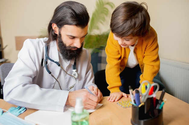 Medico pediatra che esamina un bambino in uno studio medico confortevole