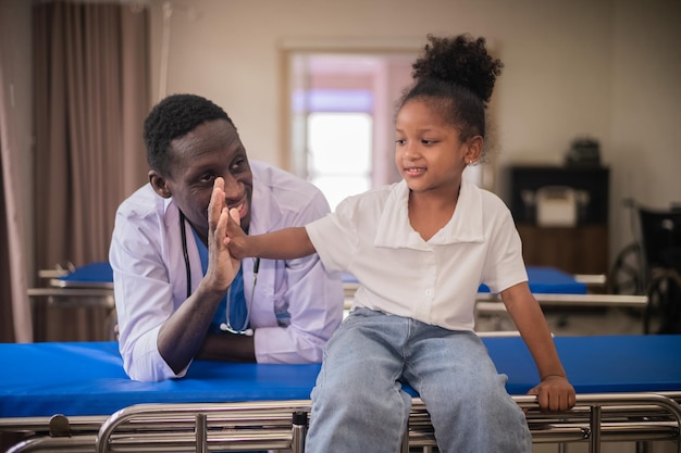 Medico pediatrico afroamericano con paziente per bambini in ospedale Pediatra maschio afroamericano