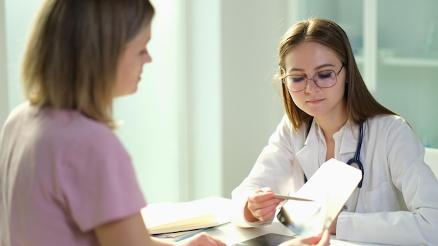 Medico pneumologo che mostra i raggi X alla donna paziente in clinica