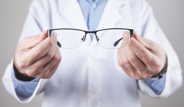 Medico professionista caucasico che mostra gli occhiali.