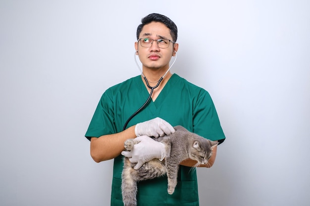 Medico scioccato in clinica veterinaria che esamina il gatto con lo stetoscopio che boccheggia stupito mentre tiene il gatto nel braccio