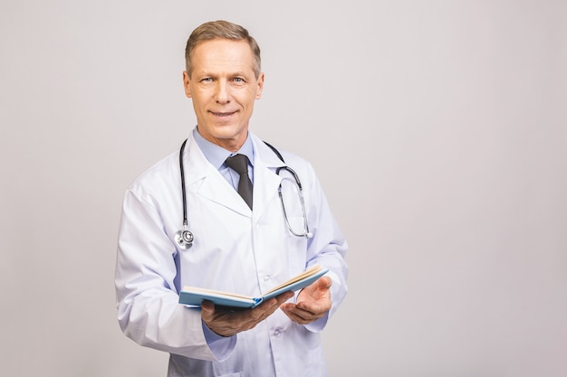 Medico senior che legge un libro isolato sopra la parete grigia.