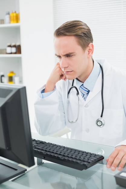 Medico serio che utilizza computer all&#39;ufficio medico