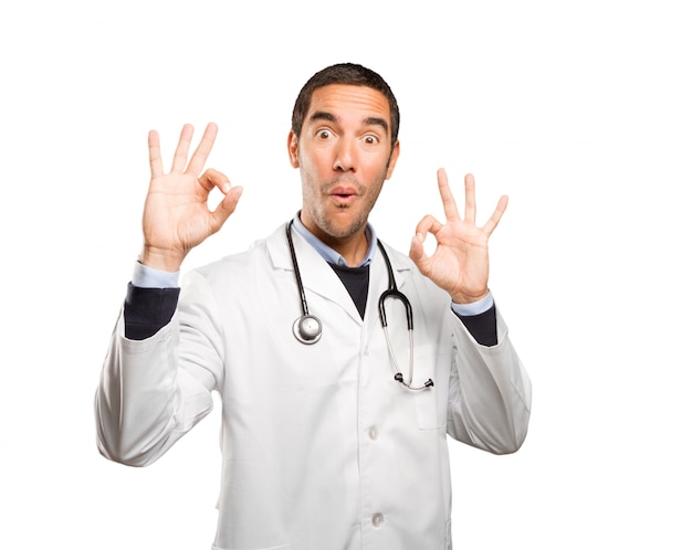 Medico soddisfatto con un gesto ok su sfondo bianco