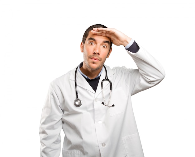 Medico sorpreso con gesto di ricerca su sfondo bianco