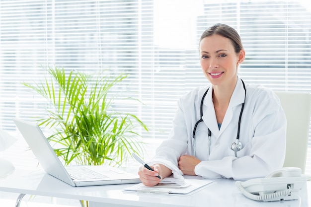 Medico sorridente allo scrittorio in clinica