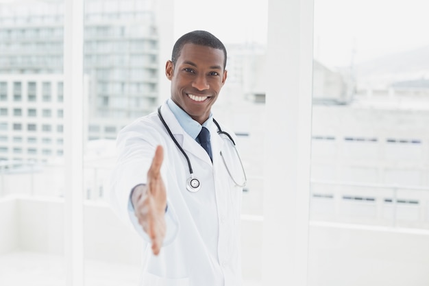 Medico sorridente che offre una stretta di mano in un ufficio medico