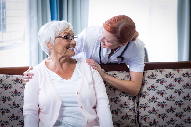 Medico sorridente che parla con donna senior felice