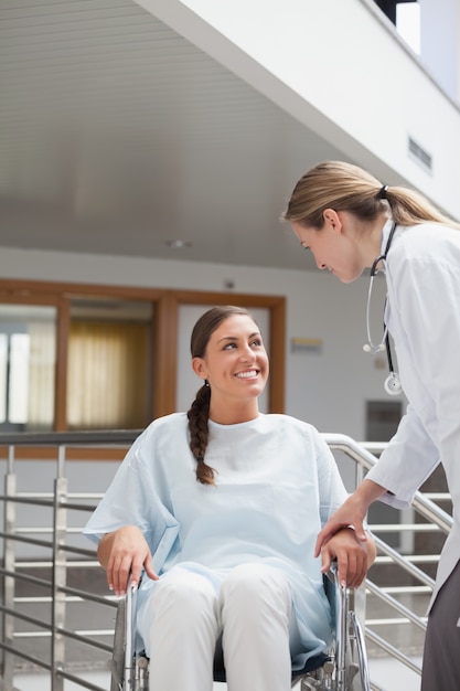 Medico sorridente che tocca un paziente su una sedia a rotelle