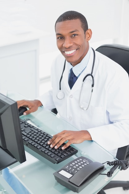 Medico sorridente che utilizza computer all&#39;ufficio medico