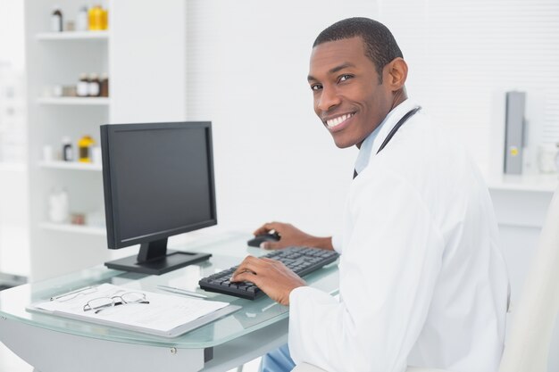 Medico sorridente che utilizza computer all&#39;ufficio medico