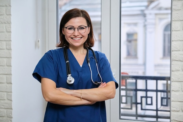 Medico sorridente della donna adulta in uniforme blu con lo stetoscopio