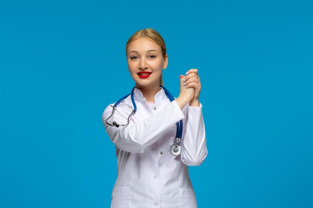 Medico sorridente della giornata mondiale dei medici che si tiene per mano con lo stetoscopio nel camice medico